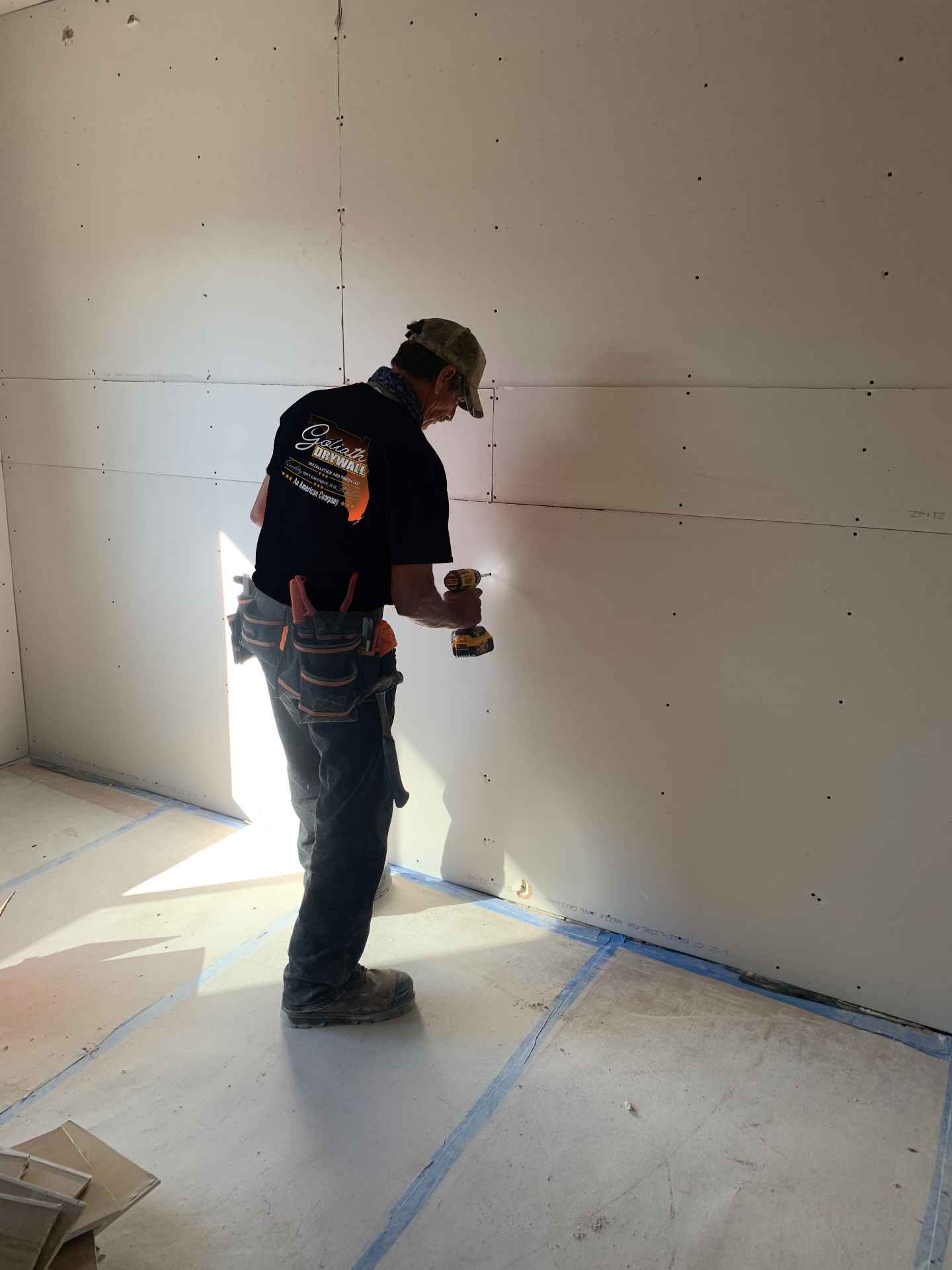 Crew member fastening fresh drywall panels during installation