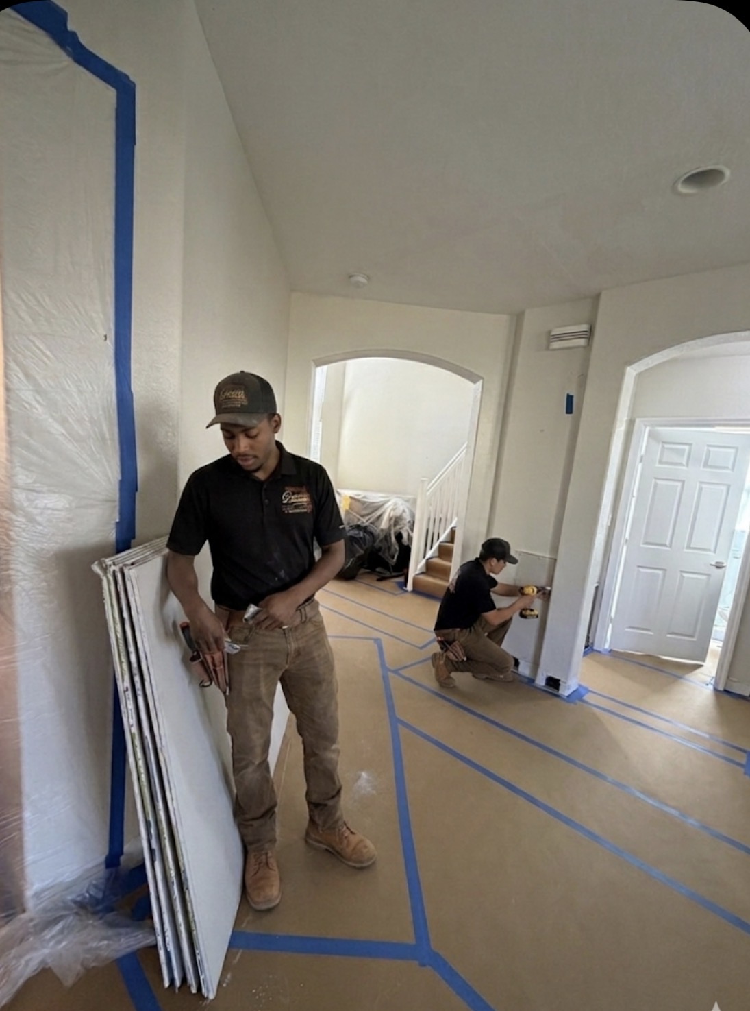 Two crew members working inside a protected home entryway