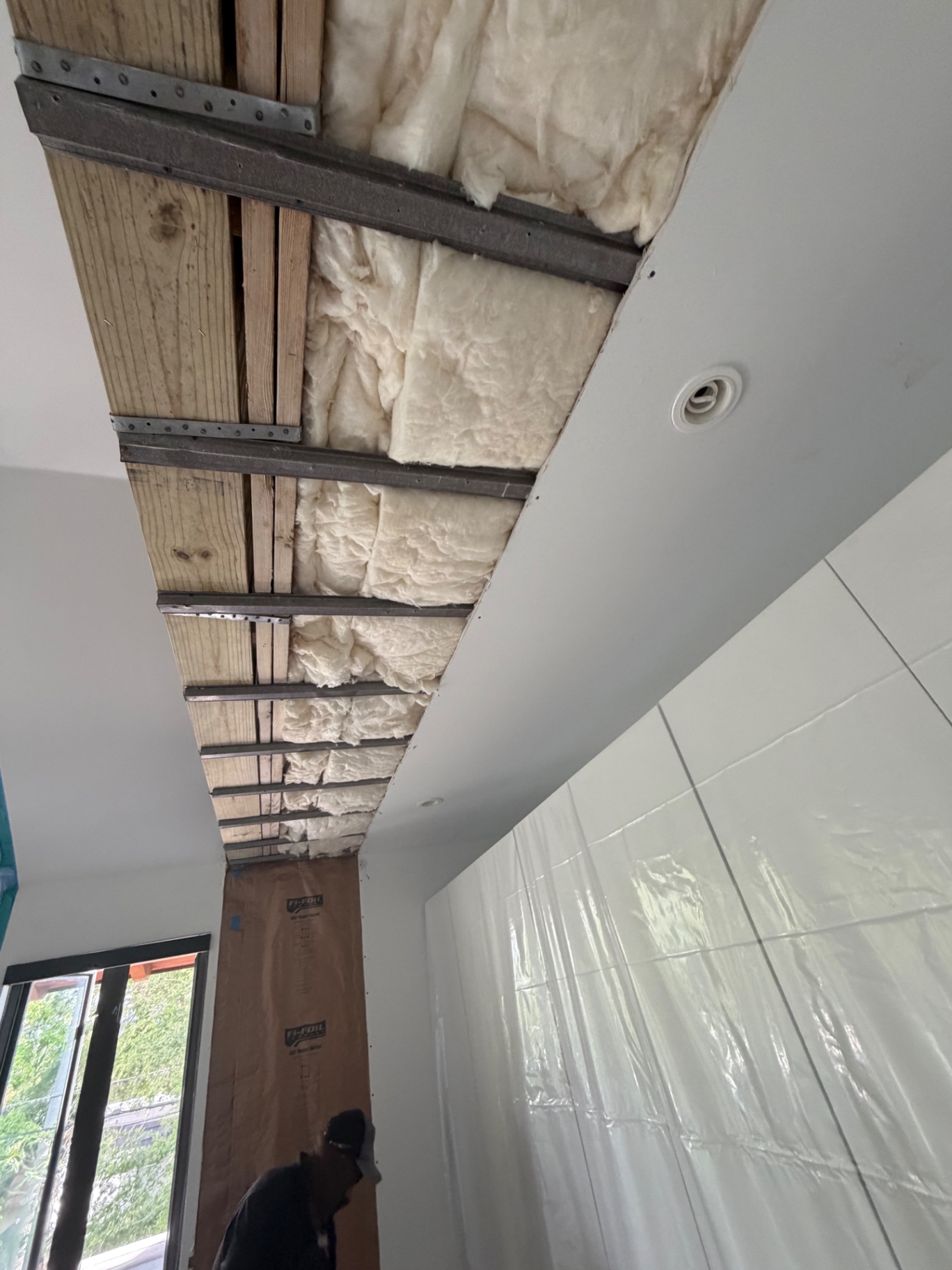 Ceiling and wall opened up after water mitigation, exposed joists and insulation bays