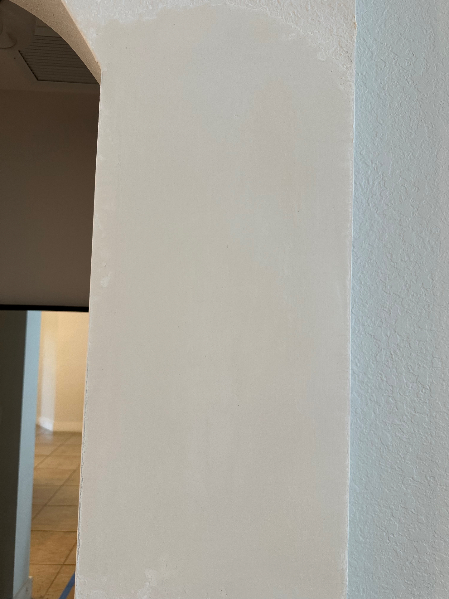 Same entryway wall after drywall, tape, mud and plaster — smooth finish ready for paint